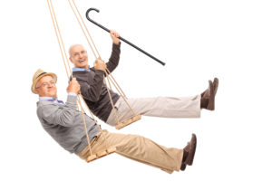 Two cheerful elderly men on wooden swings