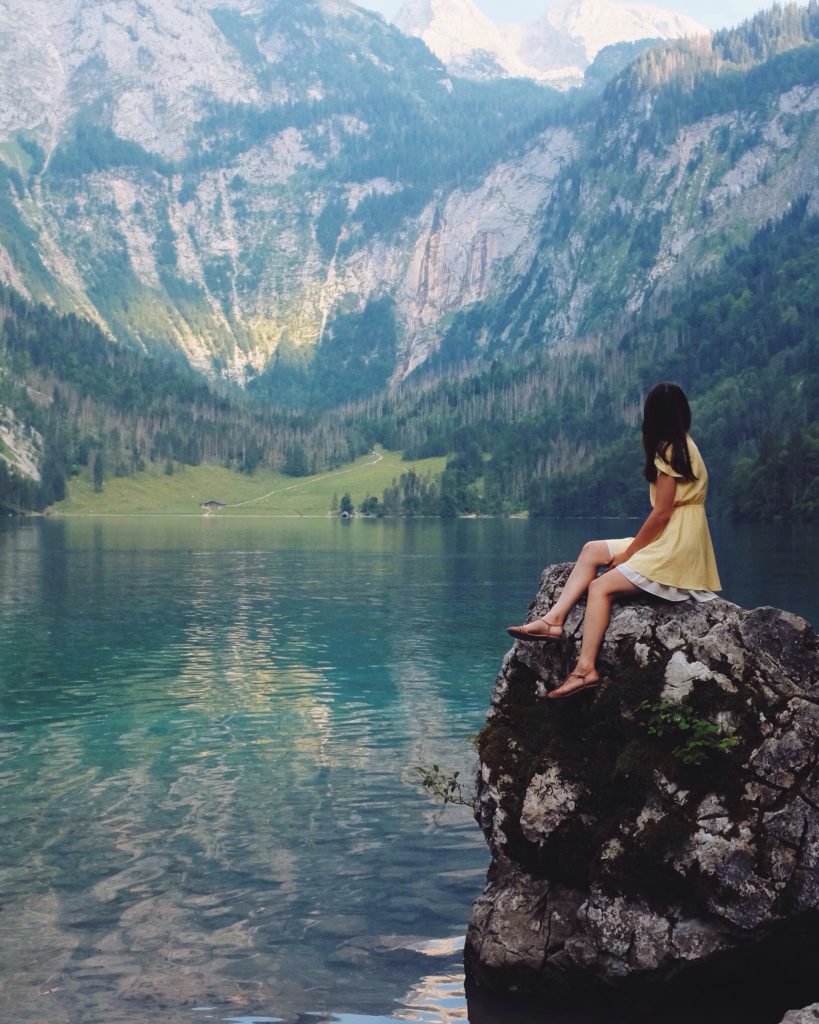 A girl perched on a rock looking out at a lake and mountains, Picture by Nadi Whatisdelirium