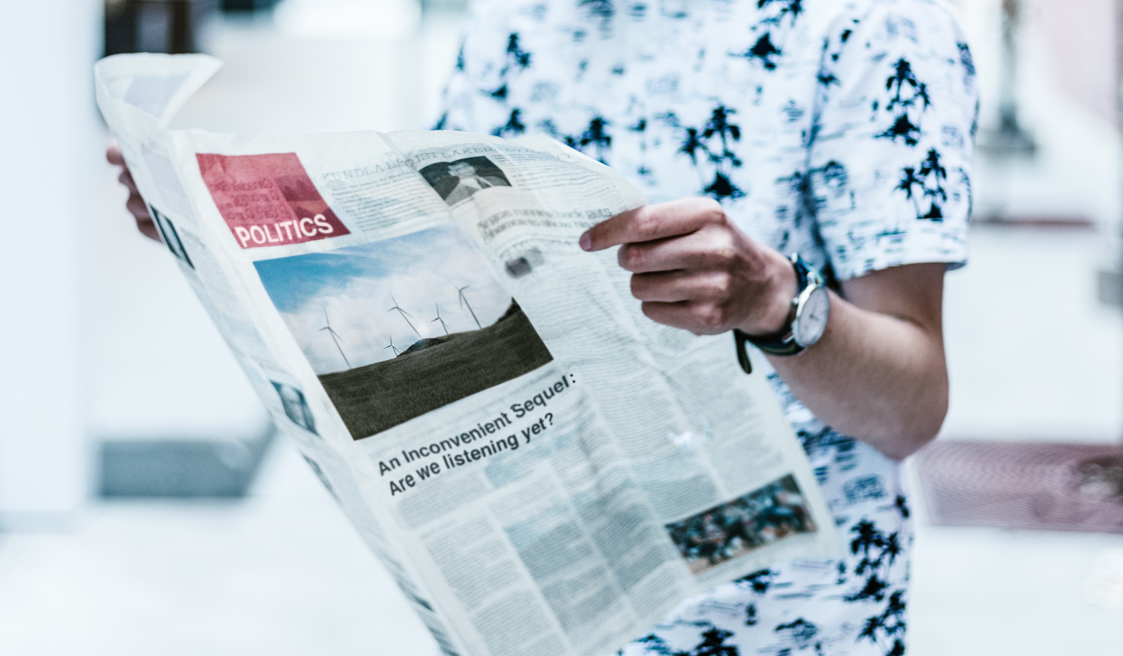 A man reading a newspaper with a feature on renewable energy and wind turbines