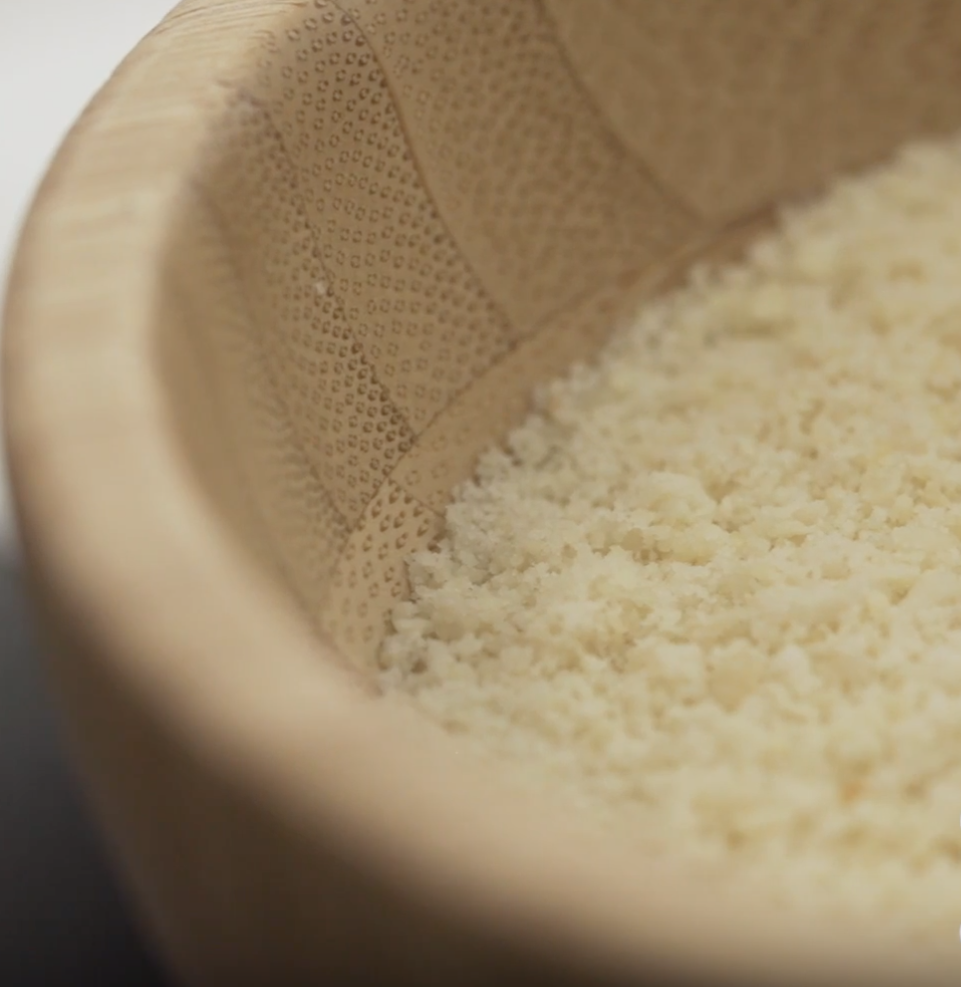 A close up of crushed almonds in a bamboo bowl.