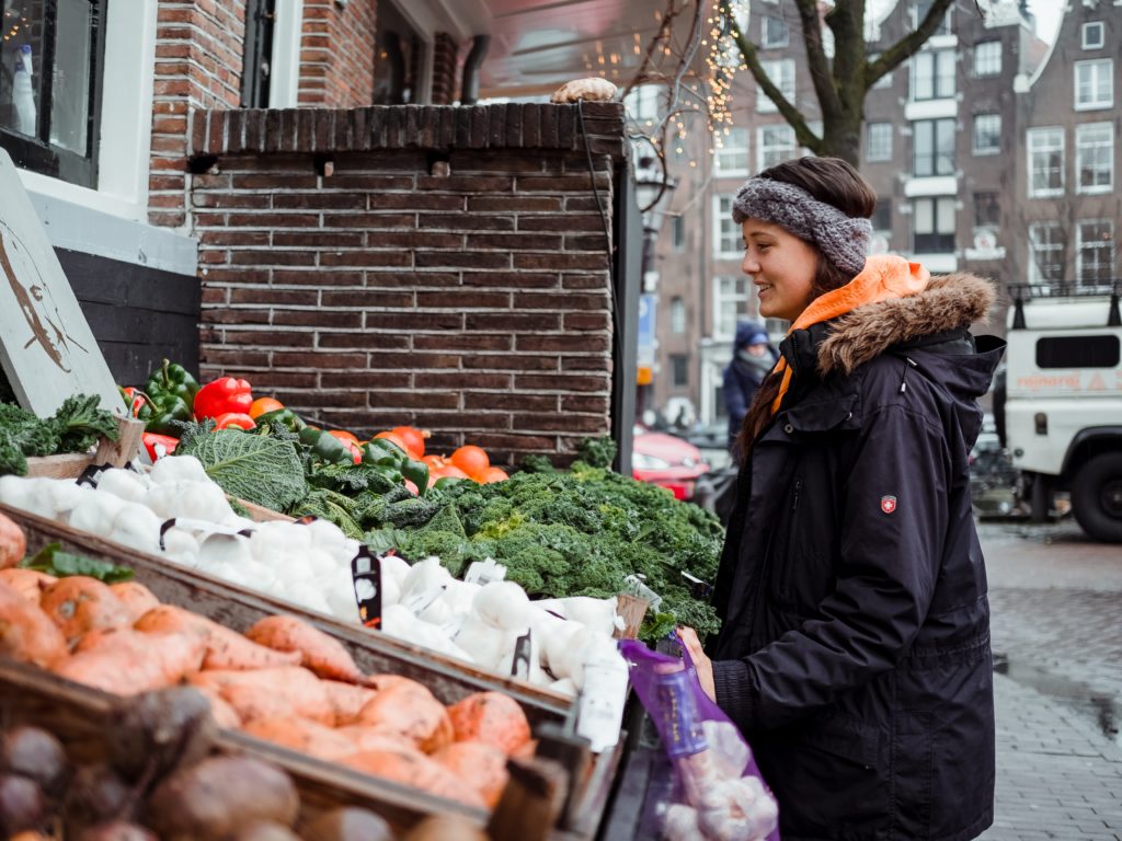 A woman picks from the fresh vegetables available at a winter market. Photo by Tembela Bohle from Pexels.